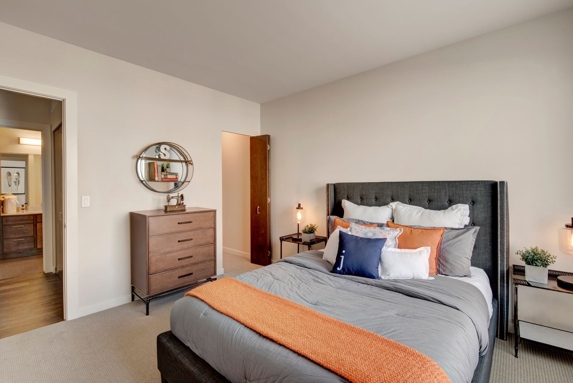 A bedroom with a bed , dresser , nightstand and mirror.