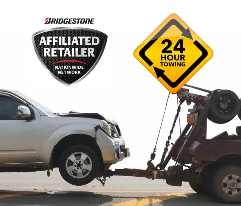 A car is being towed by a 24 hour towing sign
