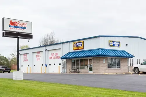 A white building with a blue roof and a white truck parked in front of it.