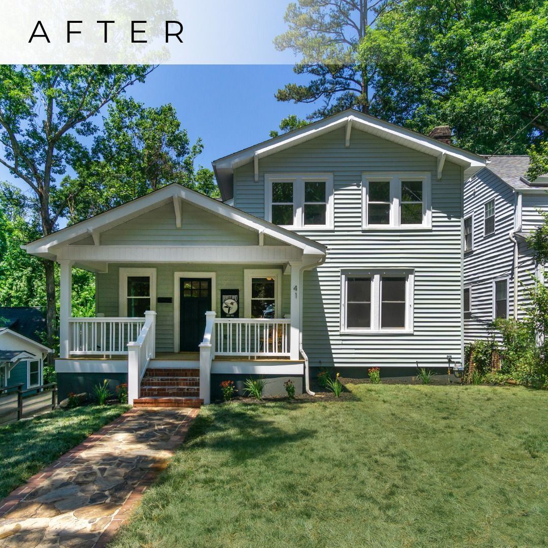 Front view of a gray two-story house with white trim, porch, and lawn under a blue sky.