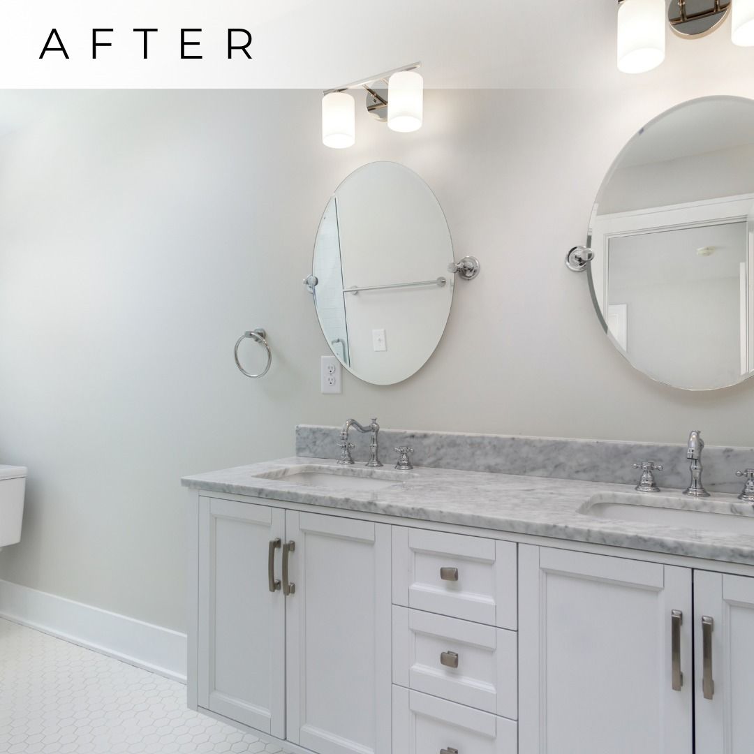 Bright white bathroom vanity with marble countertop, double sinks, oval mirrors, and wall sconces.