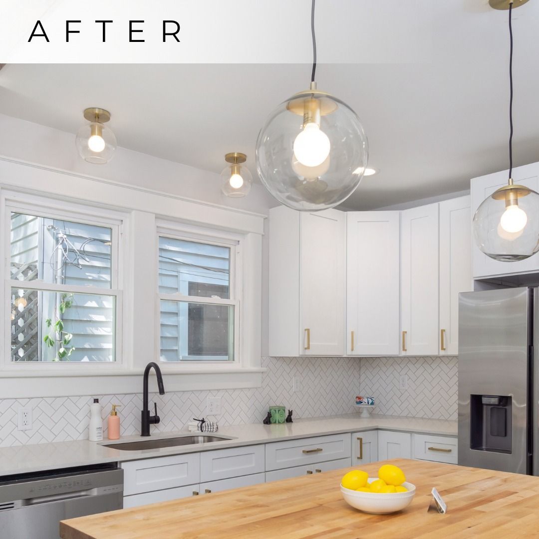 Bright white modern kitchen with island, pendant lights, stainless fridge, and bowl of lemons