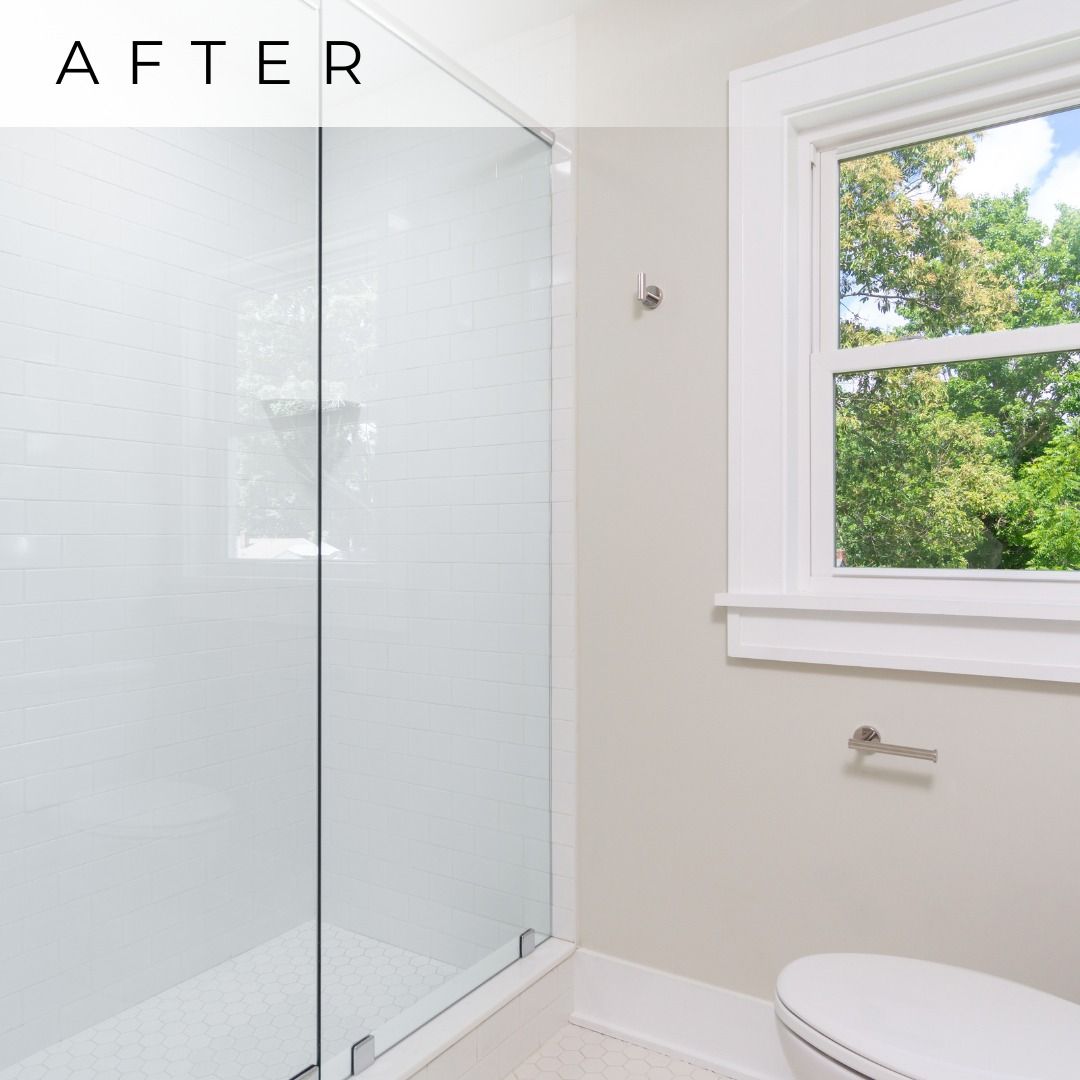 After photo of a bright bathroom with glass shower, white walls, window, and toilet