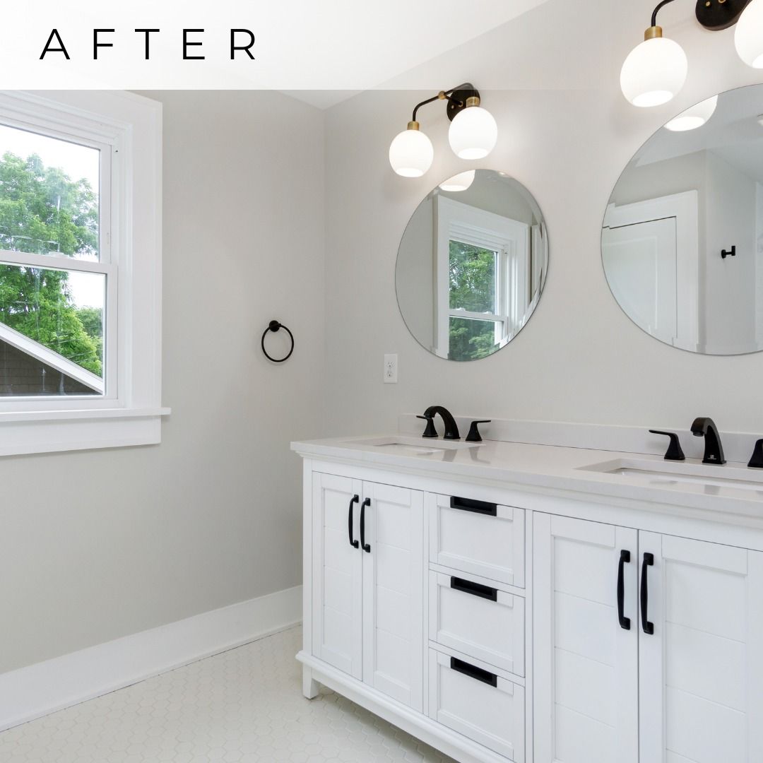 Bright modern bathroom with white vanity, round mirrors, black fixtures, and a window.