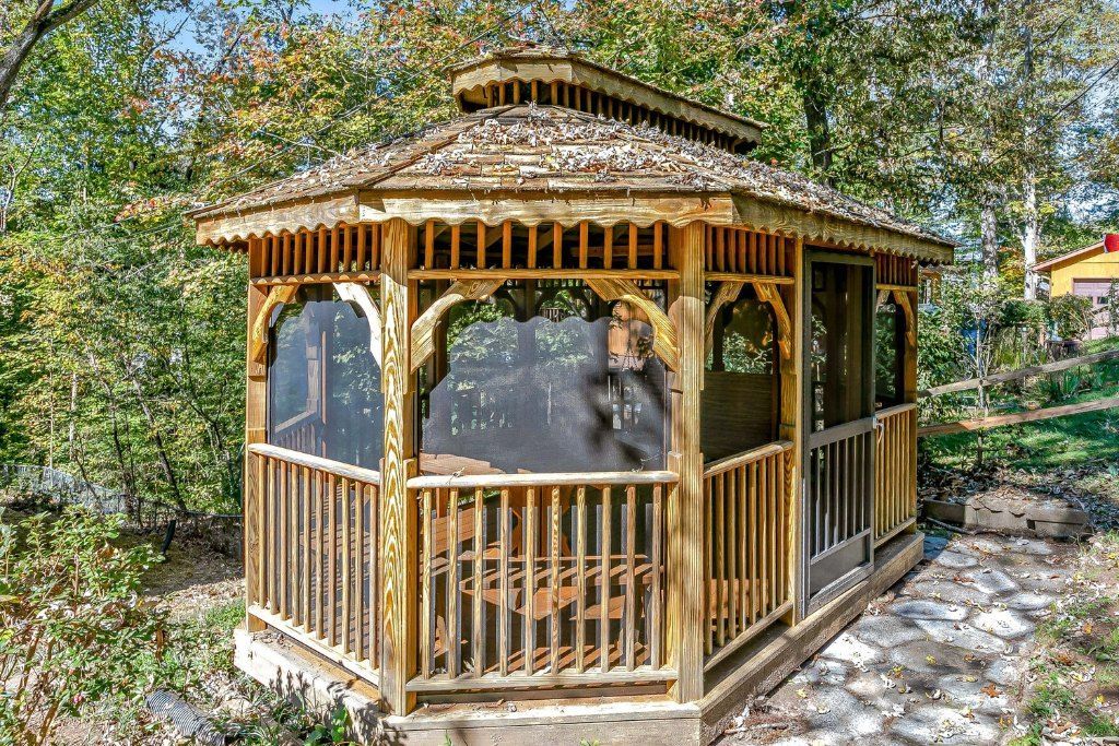 Wooden octagonal gazebo with screened windows in a leafy garden