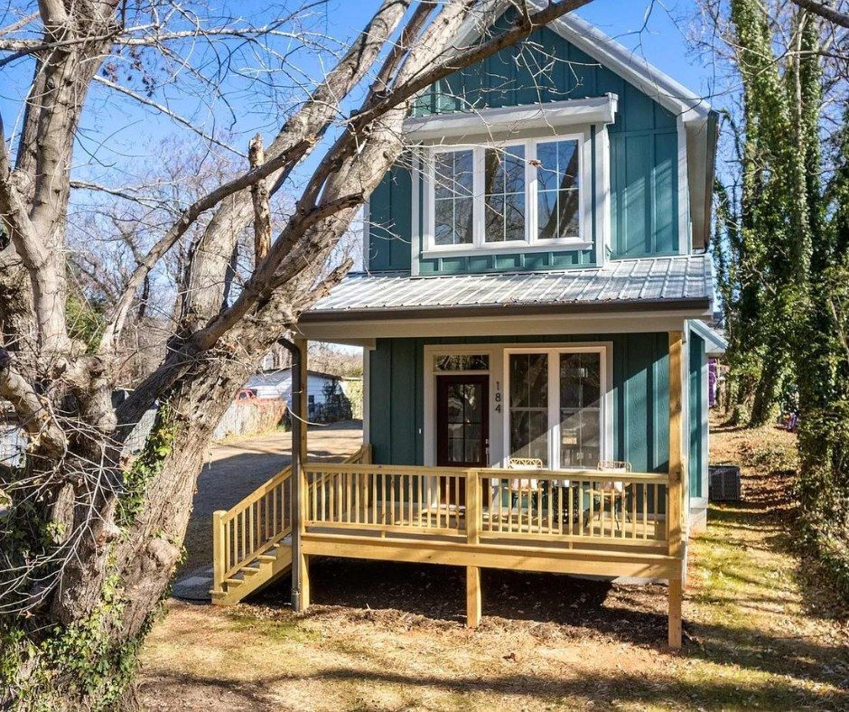 Blue two-story house with a wooden front porch and leafless trees in the yard