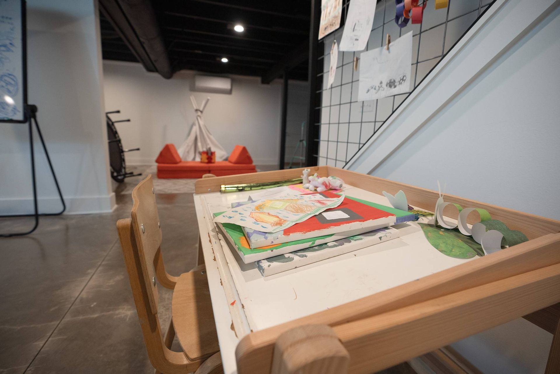 Low wooden table with books in a modern lounge area and orange chairs in the background