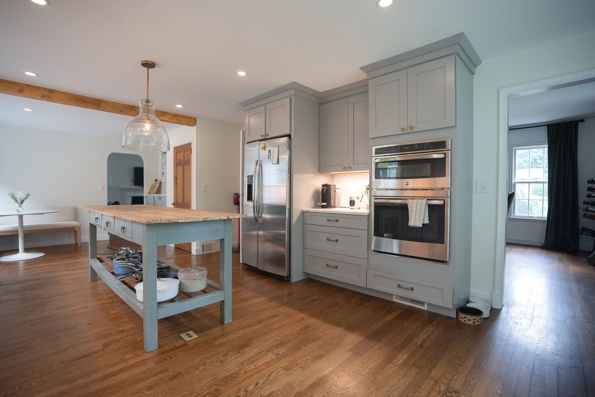 Bright modern kitchen with light blue cabinets, stainless appliances, wooden island, and hardwood floors