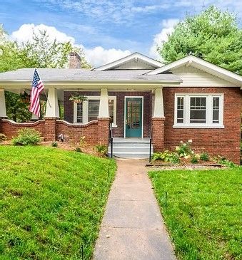 Single-story red brick house with a front walkway, porch, and an American flag
