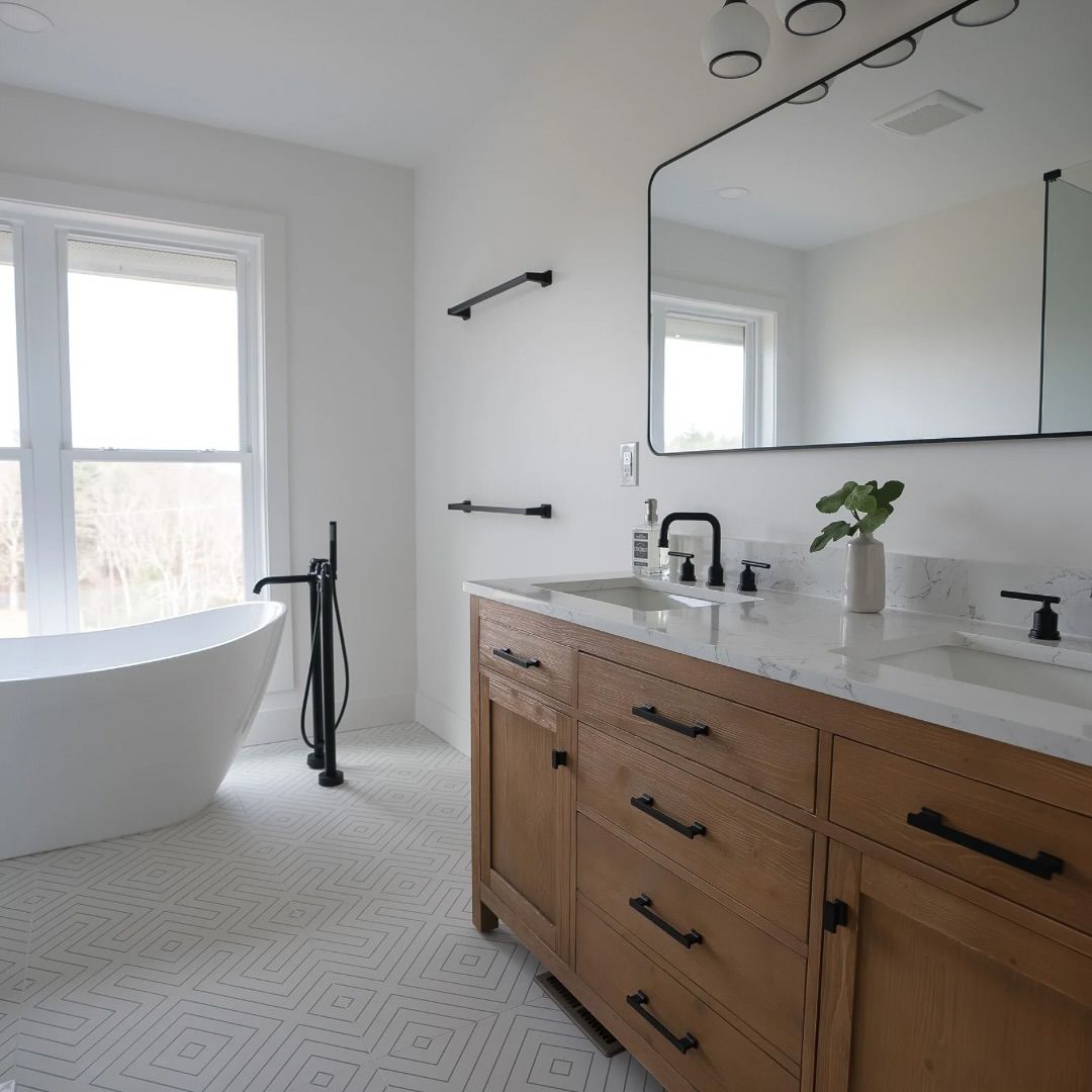 Bright modern bathroom with freestanding tub, double wooden vanity, large mirror, and tiled floor