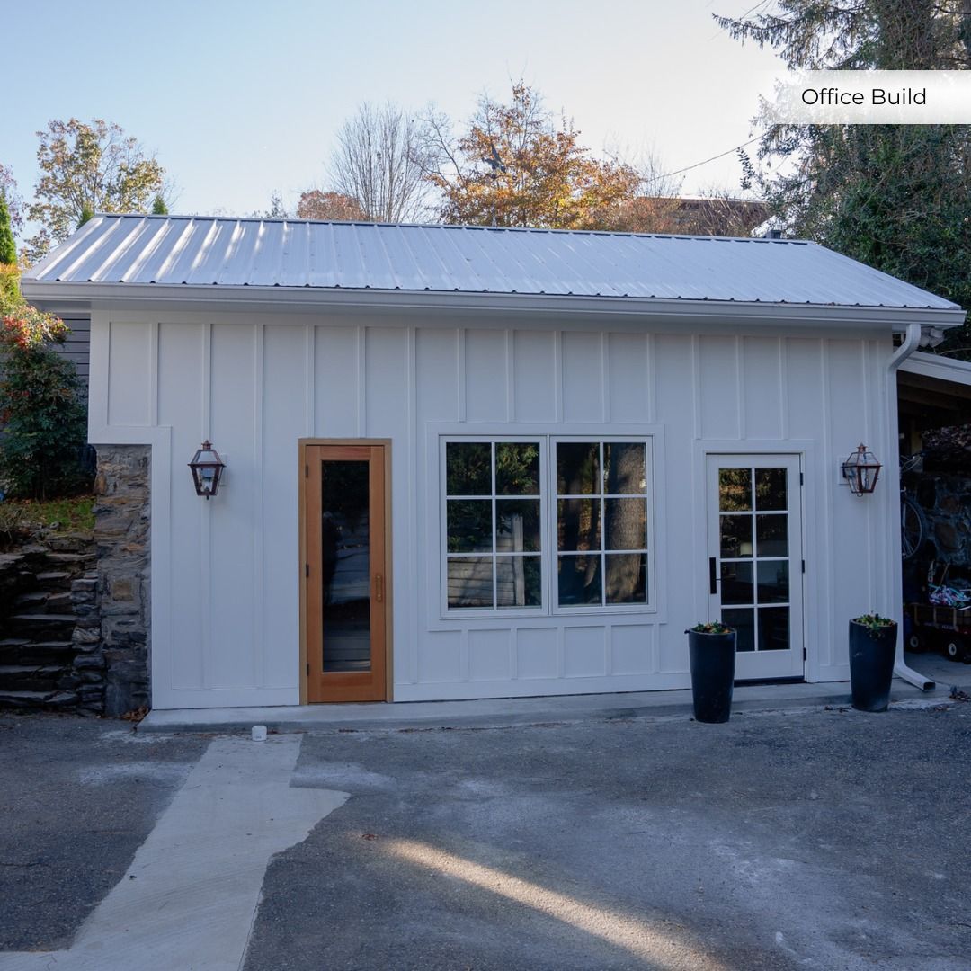 Small white storefront with a wood-framed door, large front windows, and two wall lanterns.