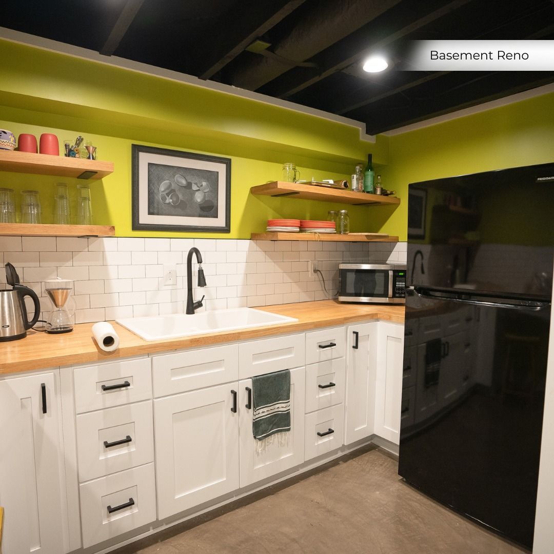 Bright modern kitchen with white cabinets, wooden countertops, green walls, open shelves, and a black fridge.