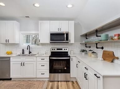 Bright modern kitchen with white cabinets, stainless appliances, and open shelves
