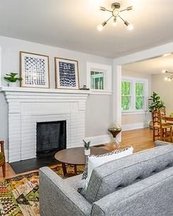 Bright living room with white fireplace, gray sofa, hardwood floor, and green plants