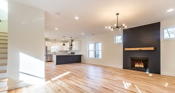 Bright open living room with hardwood floors, black fireplace wall, kitchen island, and modern ceiling lights