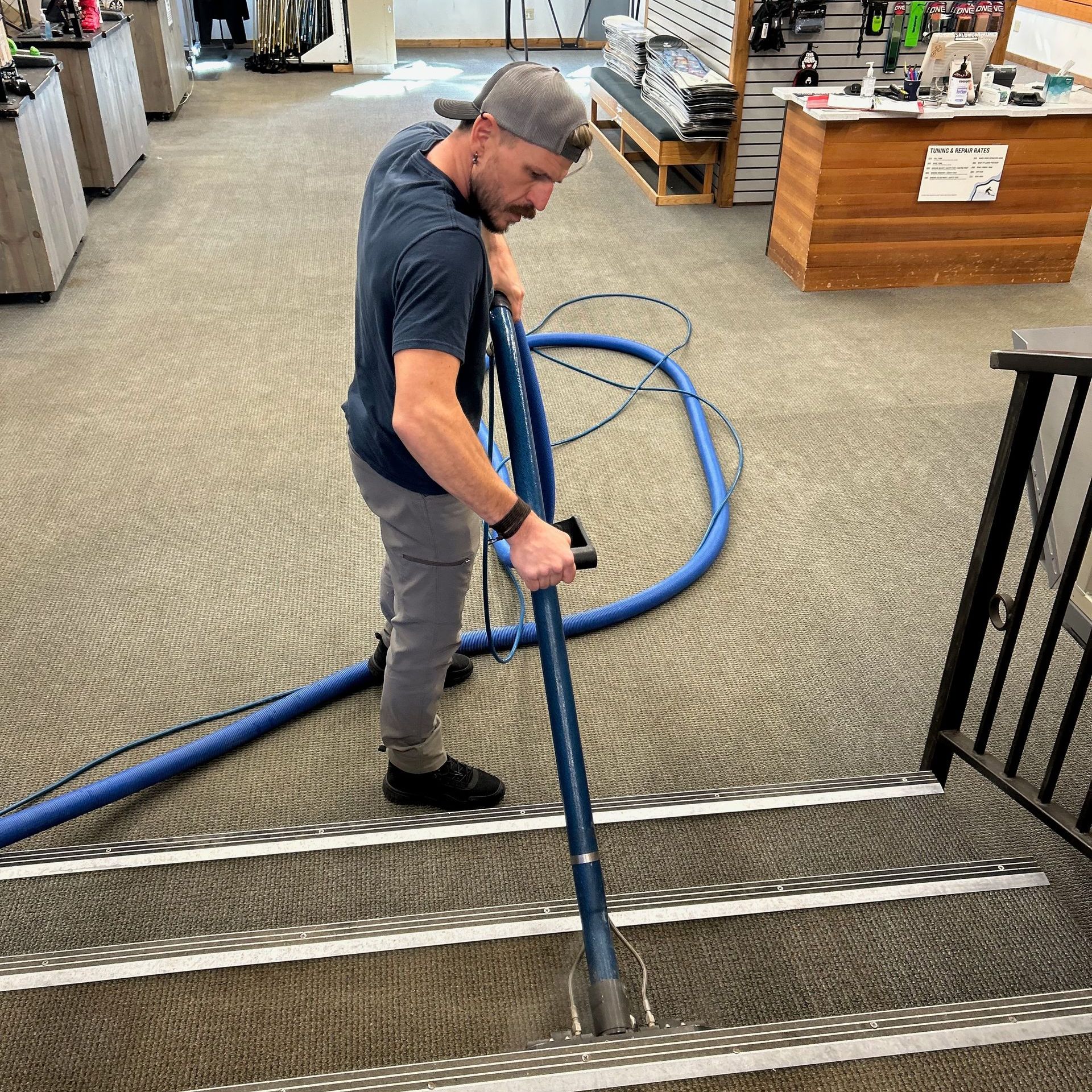 A man is using a vacuum cleaner to clean stairs in a store.