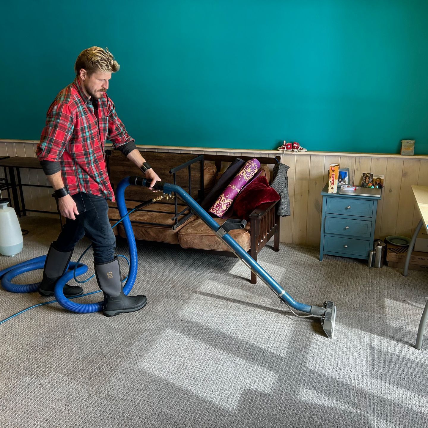 A man is using a vacuum cleaner to clean a carpet in a living room