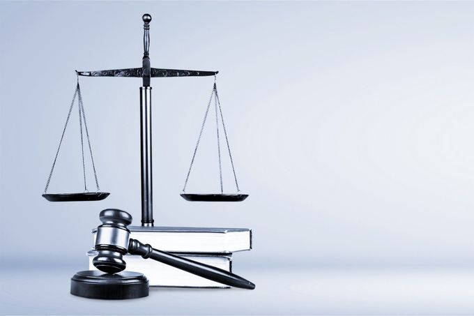 Una bilancia della giustizia e il martelletto di un giudice sono appoggiati su una pila di libri.