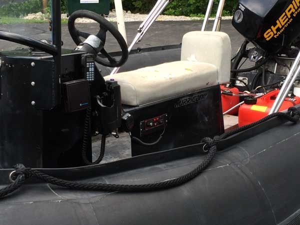 Black and white inflatable boat steering console with steering wheel, seat, and outboard motor.