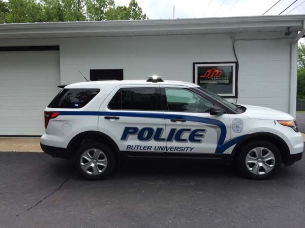 White and blue Butler University Police SUV parked outside a building.