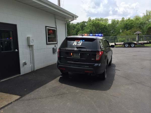 Black police SUV parked next to a white building; 