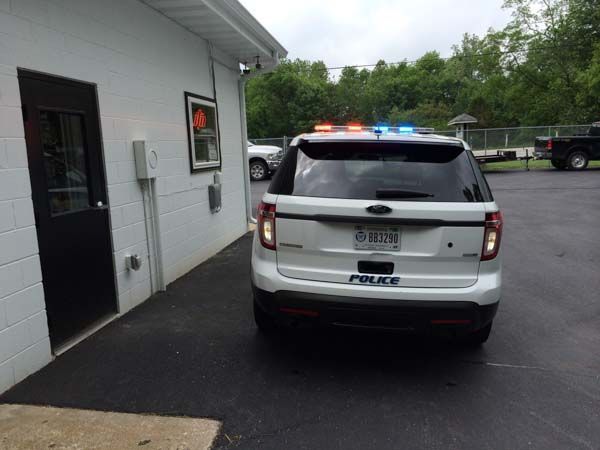 White police SUV parked next to a building; emergency lights flashing.
