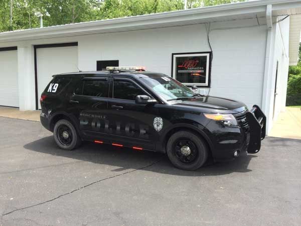 Black police SUV parked in front of a white building with garage doors. 