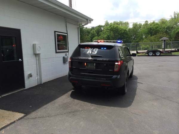 Black K9 police SUV parked near a building, with flashing blue and red lights on top.