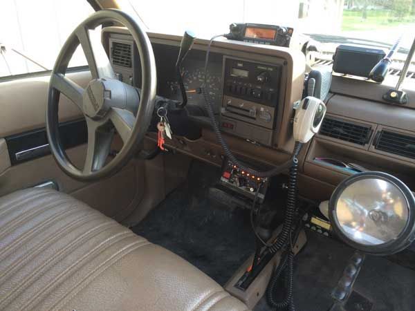 Interior of a brown pickup truck, showing the dashboard, steering wheel, and radio equipment.