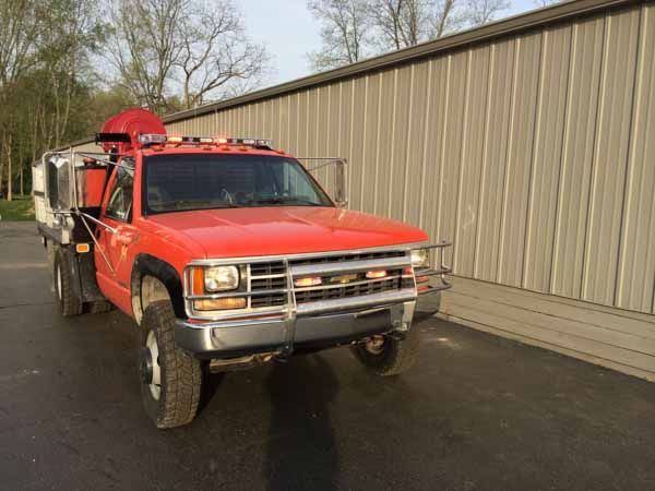 Red Chevy truck with flatbed, parked in front of a tan building.
