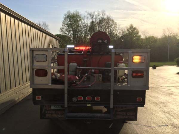Rear view of a red fire truck with emergency lights on; parked outside building.