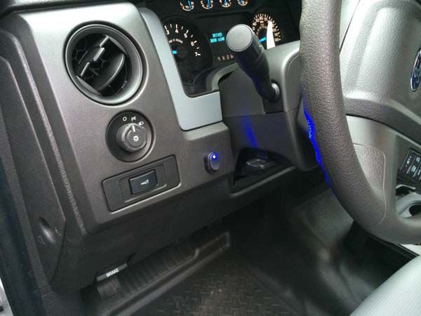Dashboard of a Ford F-150. Includes steering wheel, gauges, air vents, and a blue-lit button.