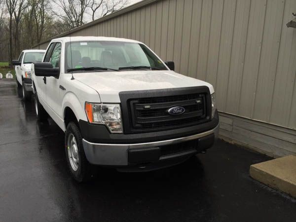 White Ford F-150 pickup truck parked outside a building. Black grille, bumper, and mirrors.