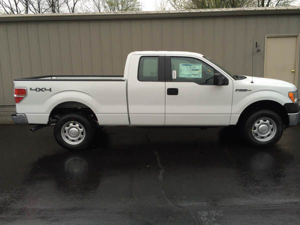 White Ford F-150 pickup truck parked outside a building on a wet surface, 4x4 emblem visible.