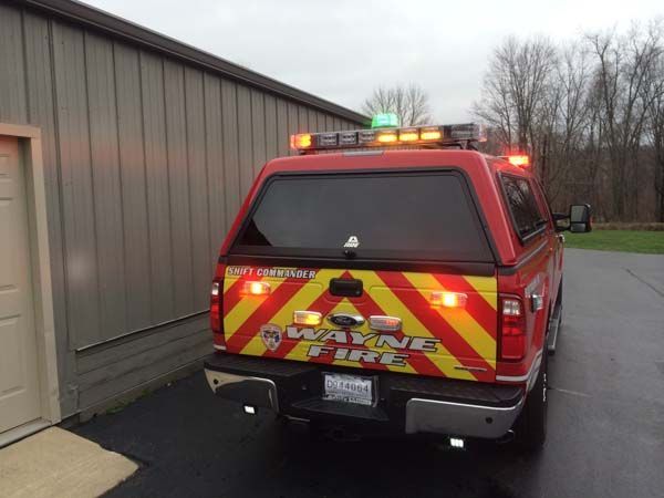 Red Wayne Fire truck parked near a building, with flashing lights.
