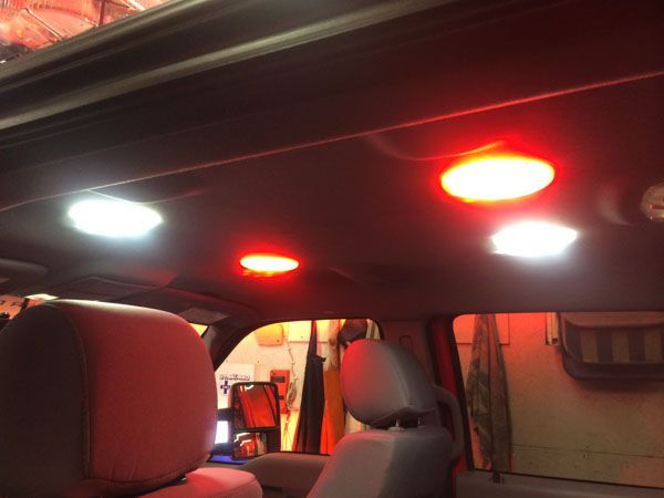 Interior car ceiling with red and white lights illuminating seats.