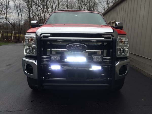 Red Ford truck with a black grill guard and bright white LED lights.