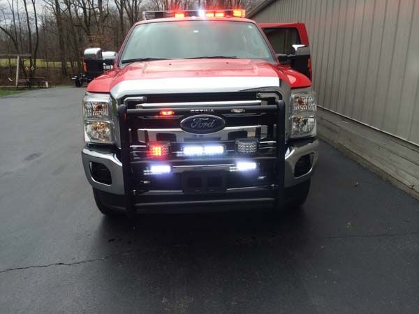 Red Ford truck with emergency lights activated; parked near a building.