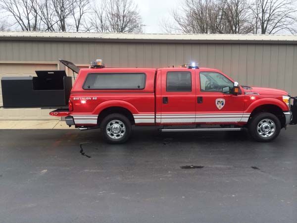 Red fire department pickup truck with a black storage box extending from the back.