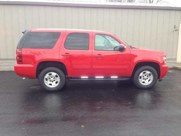Red SUV parked on wet pavement in front of a gray building.
