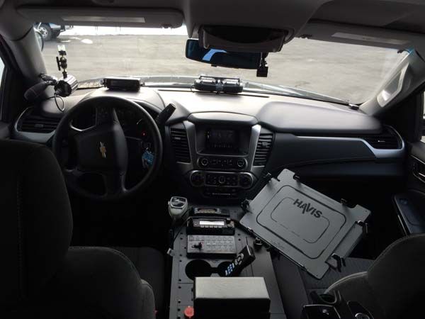 Interior of a police vehicle with dashboard, computer, and equipment visible.