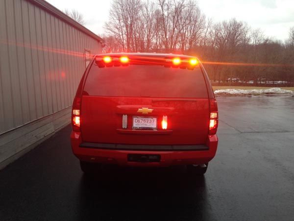 Red SUV with emergency lights flashing, parked in front of a building.