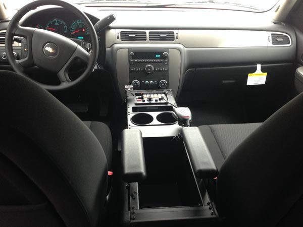 Interior view of a vehicle, showing the dashboard, steering wheel, console with cup holders, and front seats.