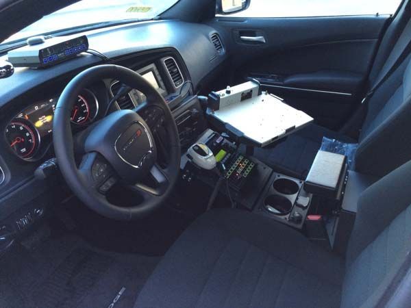 Interior of a police car with equipment, including a computer, radio, and radar unit. Black interior.