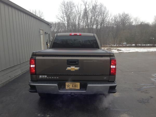 Brown Chevy Silverado truck parked, rear view. License plate visible. Near a building, outdoors.