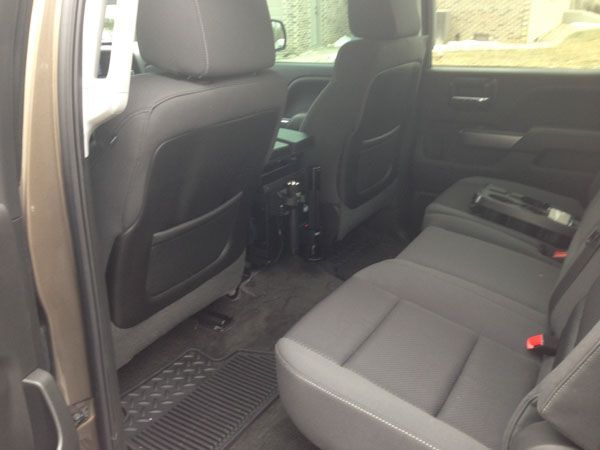 Interior view of a tan pickup truck. The back seats are gray and fabric, with black storage pockets on the backs.