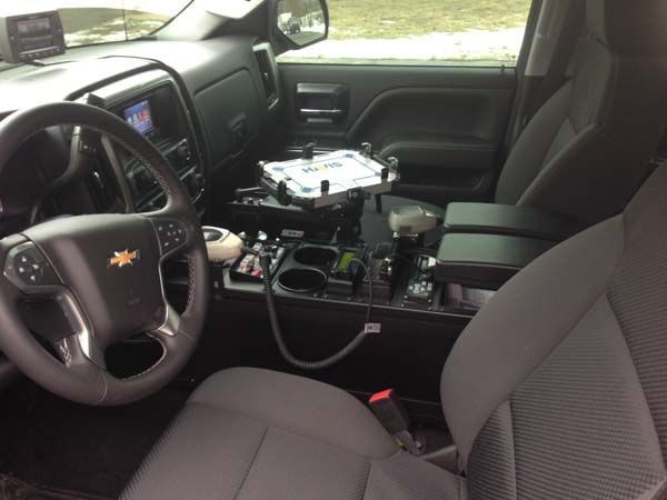 Interior of a Chevrolet truck, showing the driver's seat, dashboard, and center console, with police equipment installed.