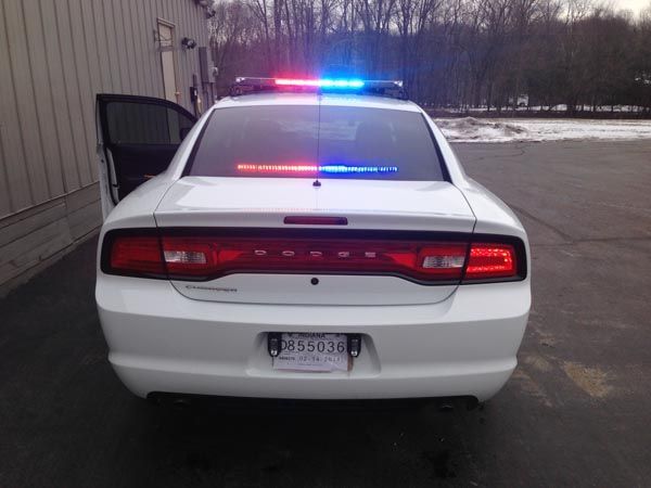 White police Dodge Charger with flashing red and blue lights, door open.