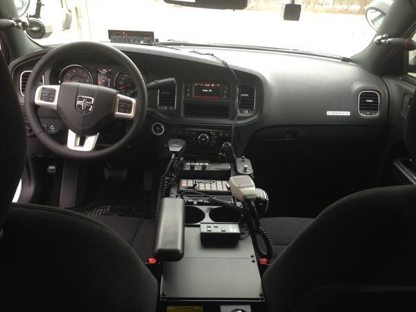 Interior of a police car with the dashboard, steering wheel, and console visible.
