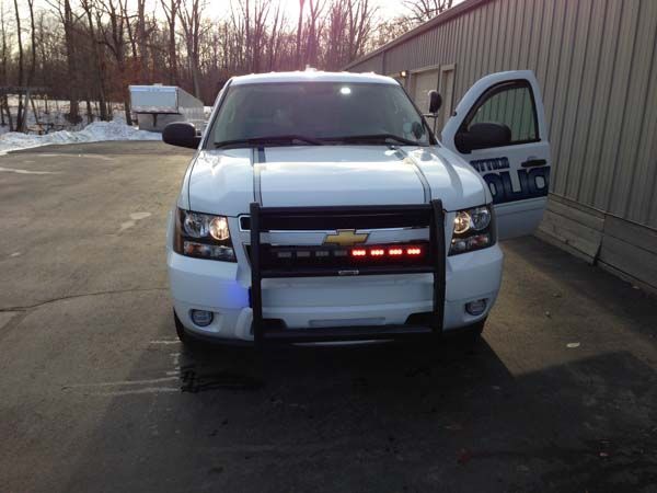 White Chevrolet police SUV with door open, visible emergency lights, and a push bar.